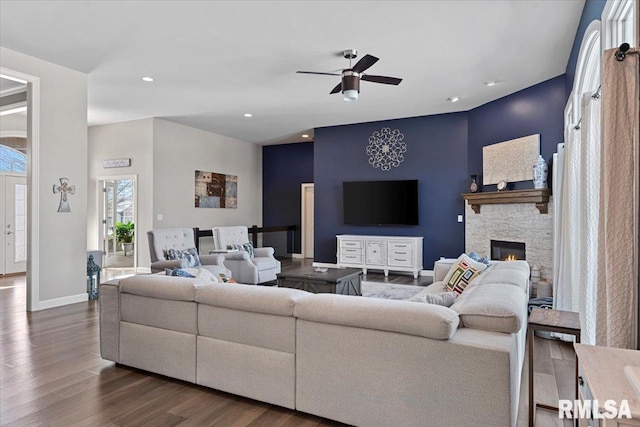 living room with a fireplace, dark wood-type flooring, and ceiling fan