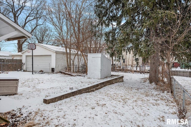 snowy yard featuring a garage and an outdoor structure