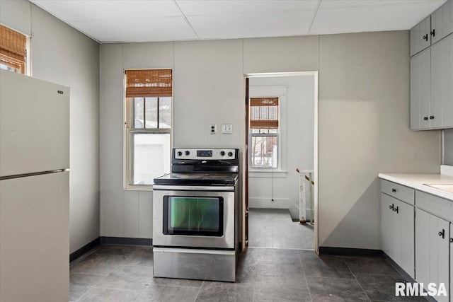 kitchen with electric stove, white cabinets, a healthy amount of sunlight, and white refrigerator