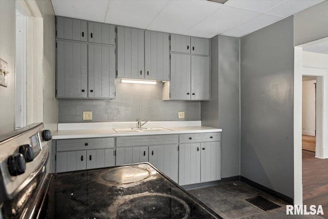 kitchen with stainless steel range, gray cabinets, and sink