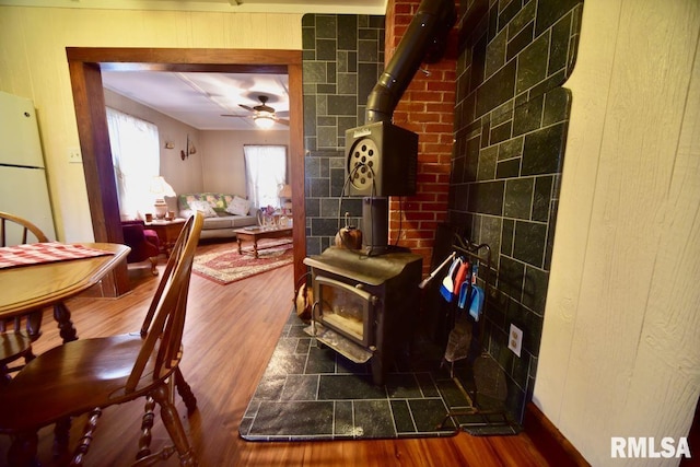 dining room with hardwood / wood-style floors, ceiling fan, and a wood stove