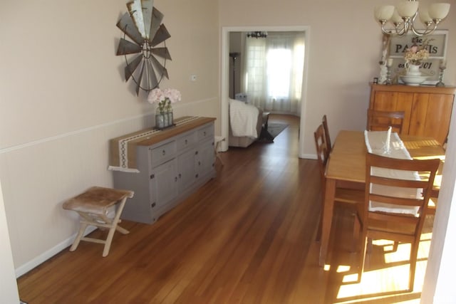 dining area with baseboards, wood finished floors, and a chandelier