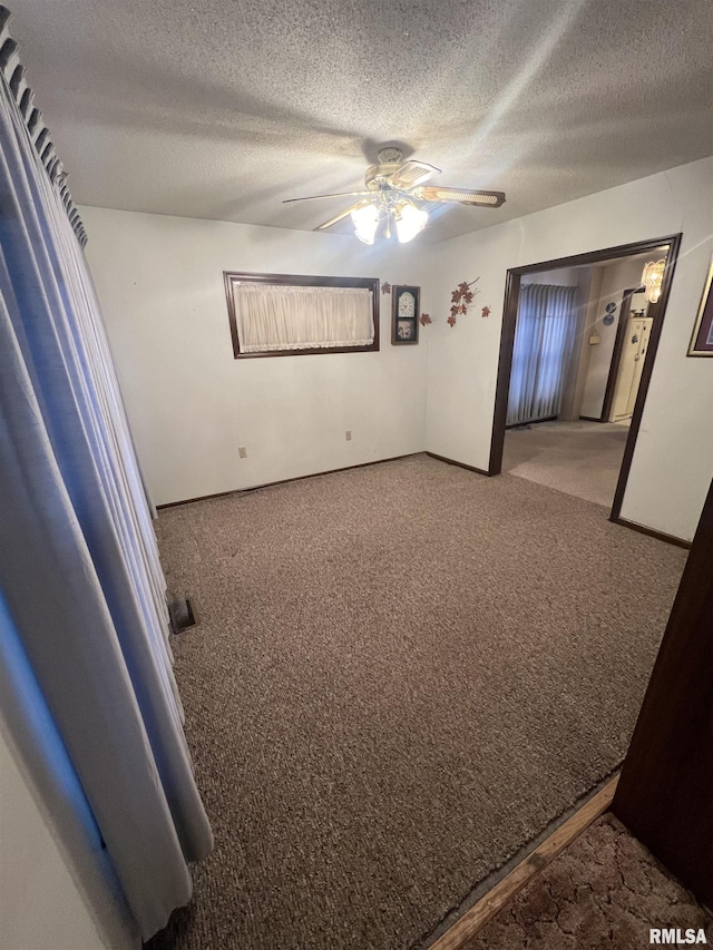 empty room featuring a textured ceiling, ceiling fan, and carpet flooring