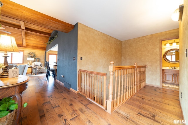 corridor featuring wood-type flooring, sink, and vaulted ceiling with beams