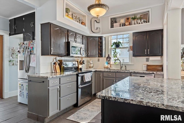 kitchen with sink, appliances with stainless steel finishes, dark brown cabinets, light stone countertops, and decorative backsplash