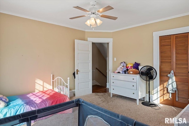 carpeted bedroom featuring ornamental molding, ceiling fan, and a closet