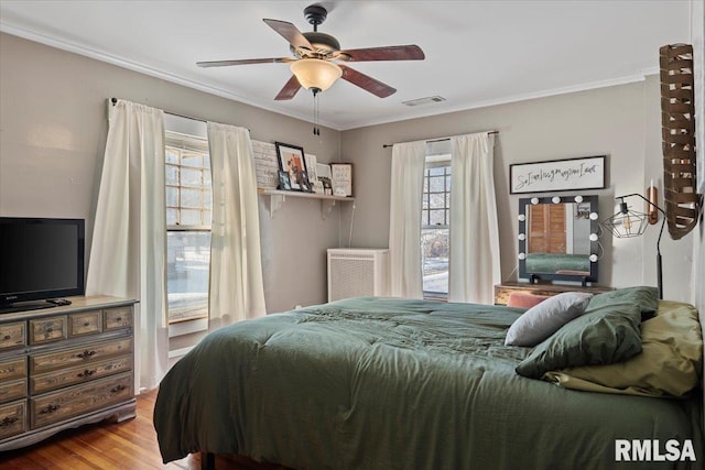 bedroom with crown molding, ceiling fan, and hardwood / wood-style flooring