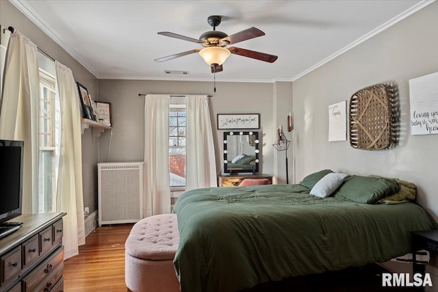 bedroom featuring crown molding, ceiling fan, radiator heating unit, and light hardwood / wood-style floors