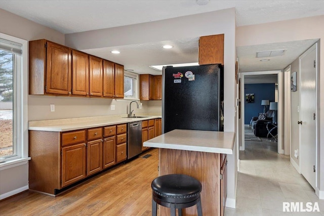 kitchen featuring sink, plenty of natural light, a kitchen breakfast bar, black fridge, and stainless steel dishwasher