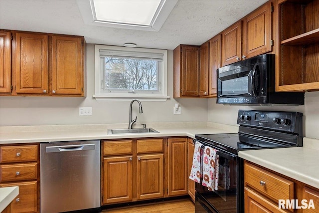 kitchen featuring sink, black appliances, light hardwood / wood-style floors, and a textured ceiling