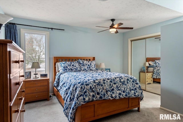 carpeted bedroom with ceiling fan, a textured ceiling, and a closet