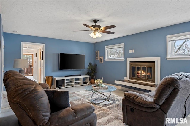 living room with ceiling fan and a textured ceiling