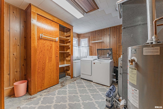 laundry room with independent washer and dryer, wooden walls, and gas water heater