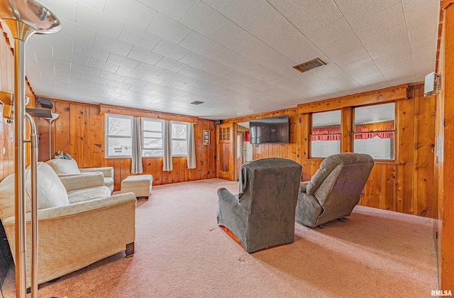 carpeted living room with wood walls