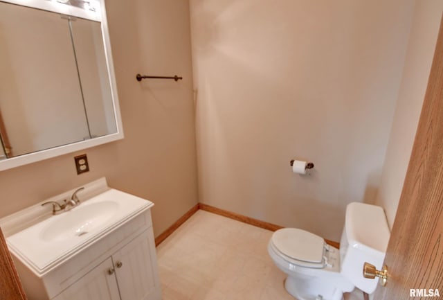 half bathroom with toilet, tile patterned floors, baseboards, and vanity