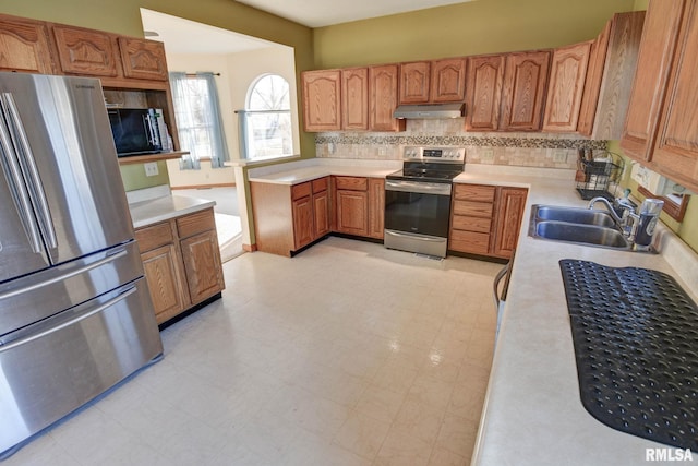 kitchen with light floors, stainless steel appliances, light countertops, a sink, and under cabinet range hood