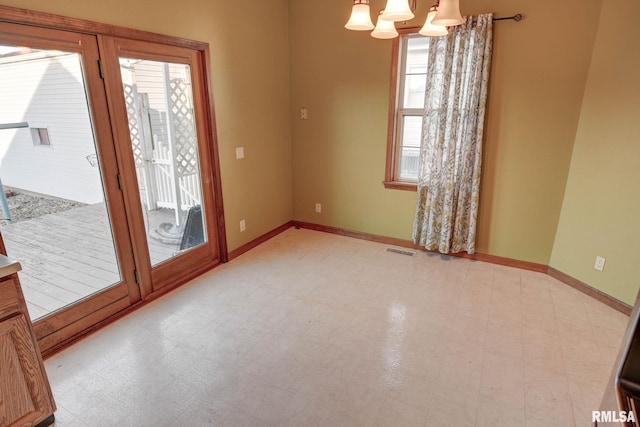 spare room featuring a chandelier, baseboards, visible vents, and tile patterned floors