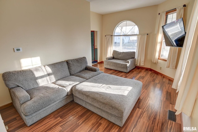 living area with wood finished floors, visible vents, and baseboards