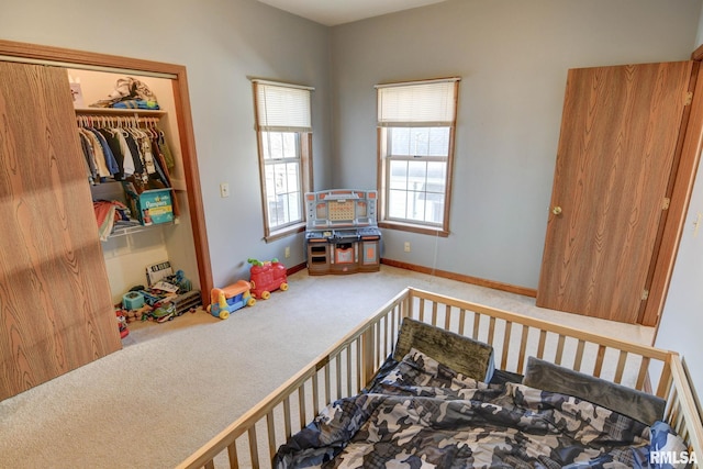 carpeted bedroom featuring a closet and baseboards