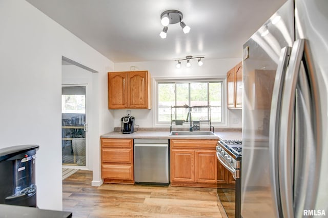 kitchen with a sink, light countertops, light wood-style floors, and stainless steel appliances