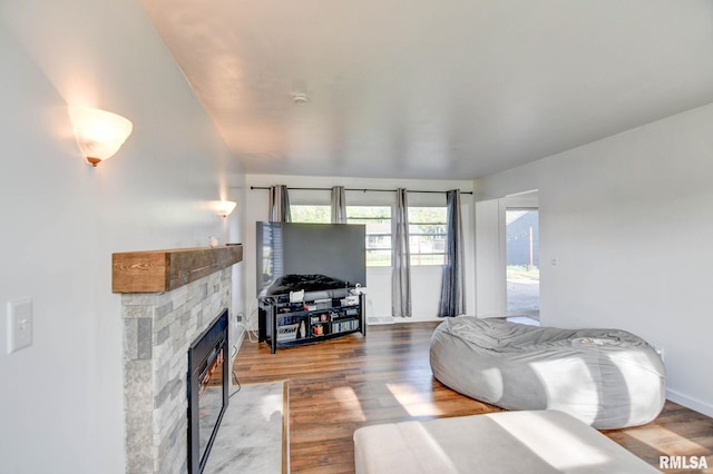 living area featuring baseboards, wood finished floors, and a fireplace