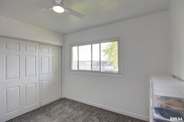 unfurnished bedroom featuring baseboards, ceiling fan, a closet, and dark colored carpet