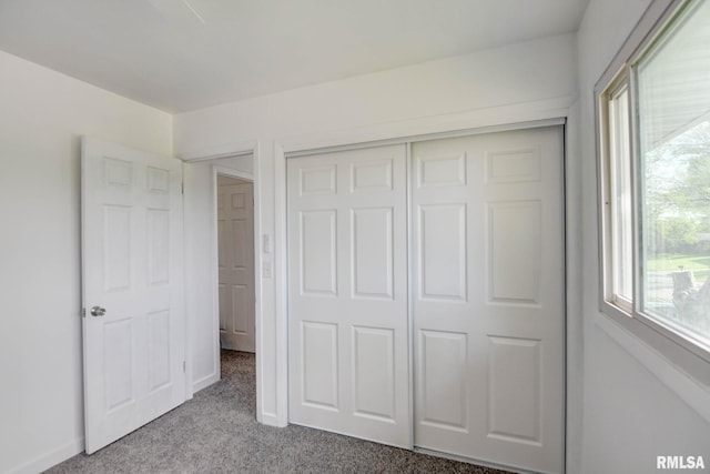 unfurnished bedroom featuring carpet floors, baseboards, and a closet