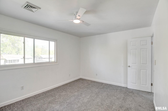 carpeted spare room with visible vents, a ceiling fan, and baseboards