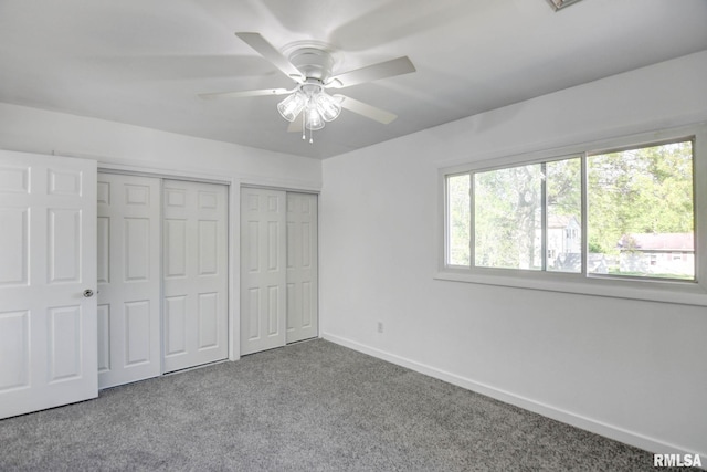 unfurnished bedroom featuring two closets, carpet flooring, ceiling fan, and baseboards