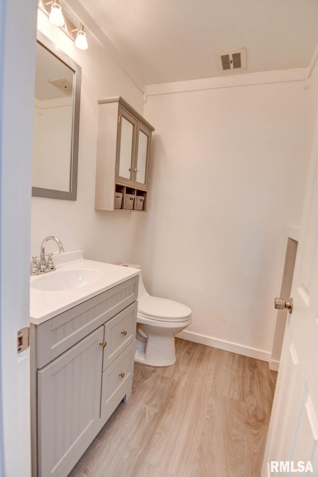 bathroom with vanity, toilet, wood finished floors, and visible vents