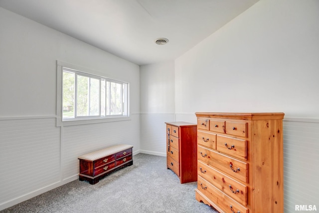 bedroom with a wainscoted wall, light carpet, and visible vents