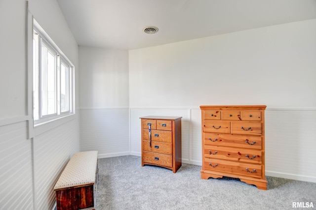 living area featuring carpet floors, baseboards, a wainscoted wall, and visible vents