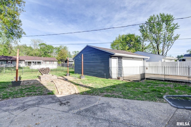 view of yard featuring a detached garage, fence, and an outbuilding