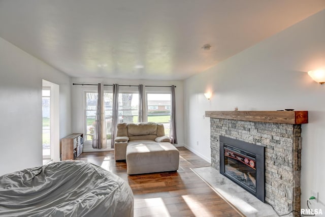 bedroom with baseboards, multiple windows, wood finished floors, and a fireplace