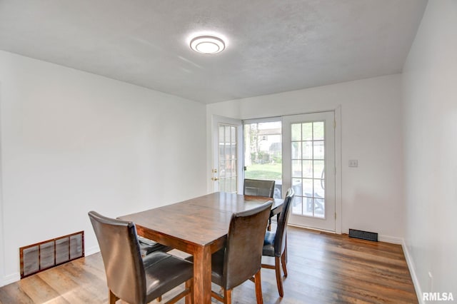 dining space featuring baseboards, wood finished floors, and visible vents