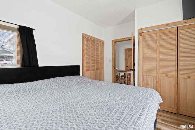 bedroom featuring multiple closets and light hardwood / wood-style floors