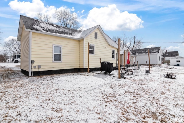 snow covered back of property with a fire pit