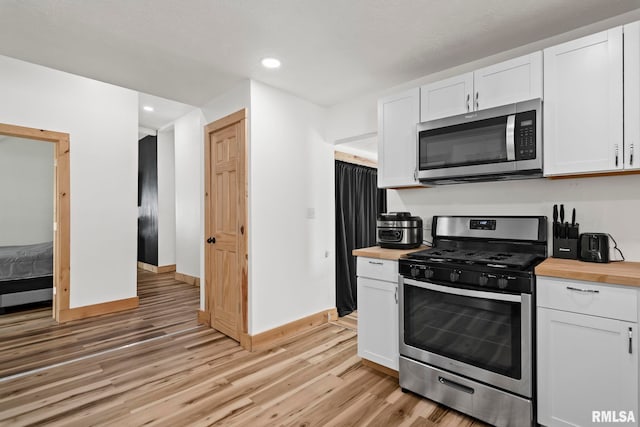 kitchen with light wood-type flooring, white cabinets, stainless steel appliances, and wood counters