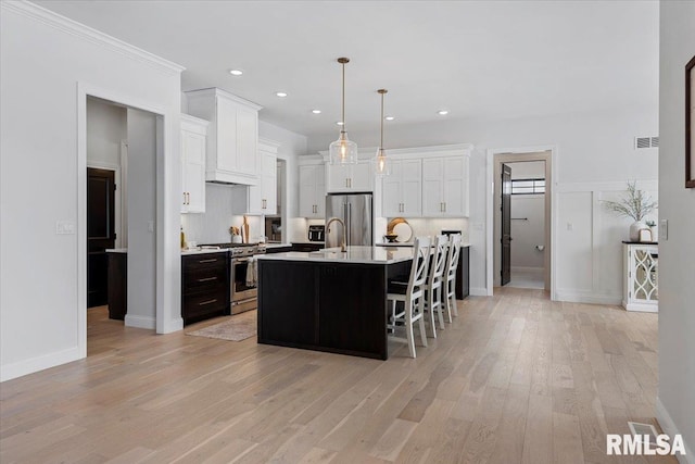 kitchen featuring light countertops, stainless steel appliances, white cabinets, and light wood-style floors