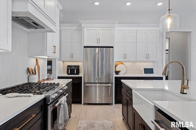 kitchen with light countertops, high end appliances, white cabinets, and custom range hood