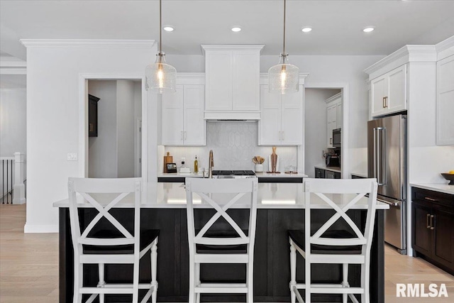kitchen featuring high end refrigerator, tasteful backsplash, white cabinets, and light countertops