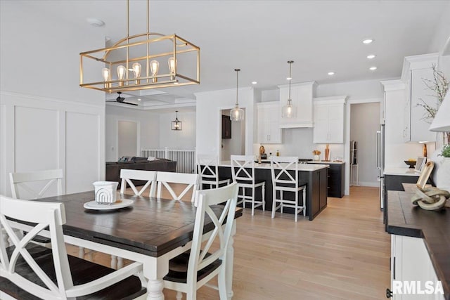 dining room featuring a wainscoted wall, a chandelier, light wood-style floors, a decorative wall, and recessed lighting