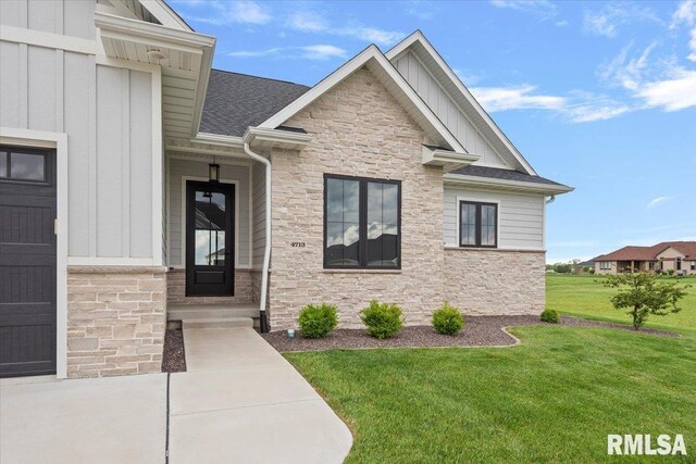 exterior space with a shingled roof, a front lawn, board and batten siding, and stone siding