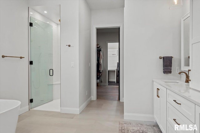 bathroom with baseboards, a freestanding tub, a spacious closet, and a shower stall
