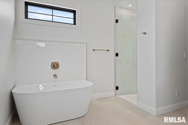 bathroom featuring baseboards, a shower stall, and a soaking tub