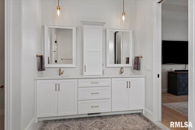 bathroom featuring a sink, baseboards, double vanity, and visible vents