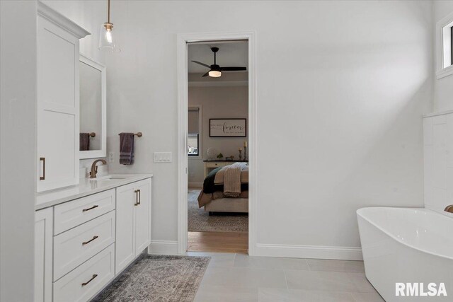 bathroom with ceiling fan, a freestanding tub, vanity, baseboards, and ensuite bathroom