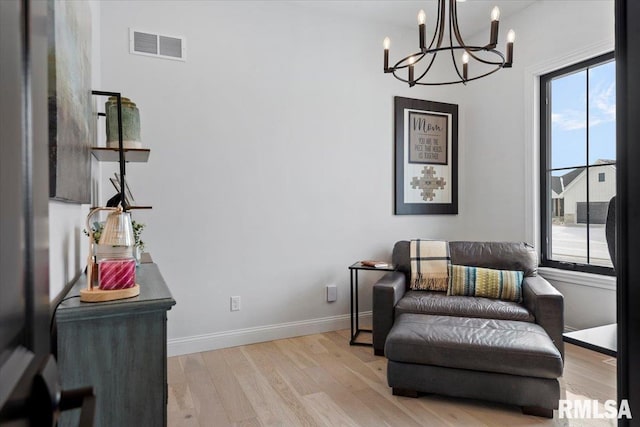 sitting room with plenty of natural light, visible vents, wood finished floors, and a chandelier
