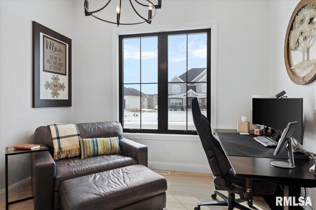 home office featuring baseboards, light wood finished floors, a notable chandelier, and a healthy amount of sunlight
