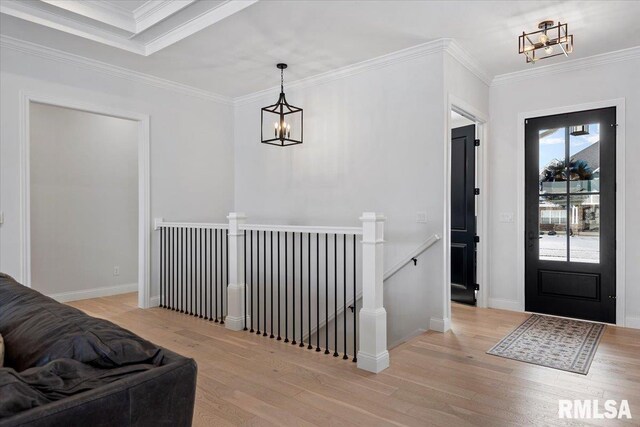 foyer entrance featuring crown molding, baseboards, light wood finished floors, and a chandelier